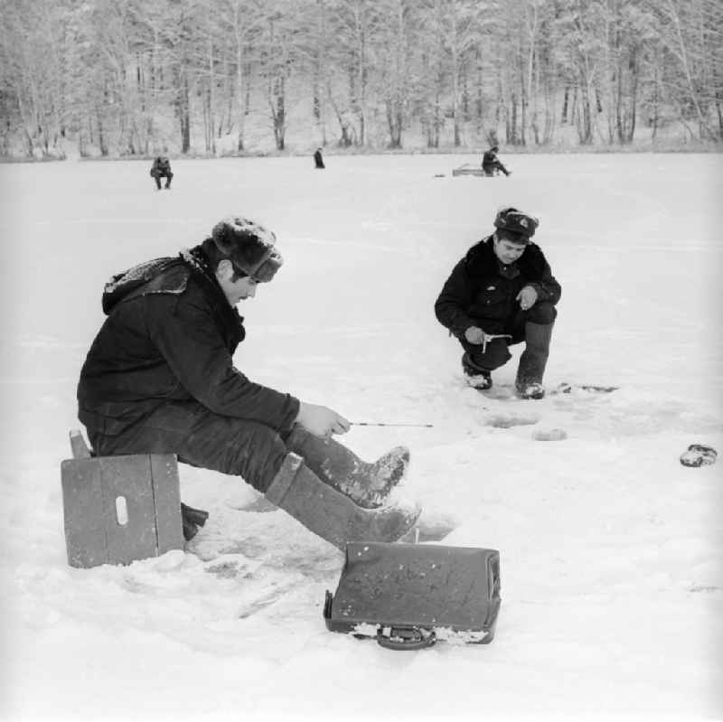 Russian soldiers in winter uniforms with the ice fish on the small Baalsee in Wittstock / Dosse in the federal state Brandenburg in the area of the former GDR, German democratic republic