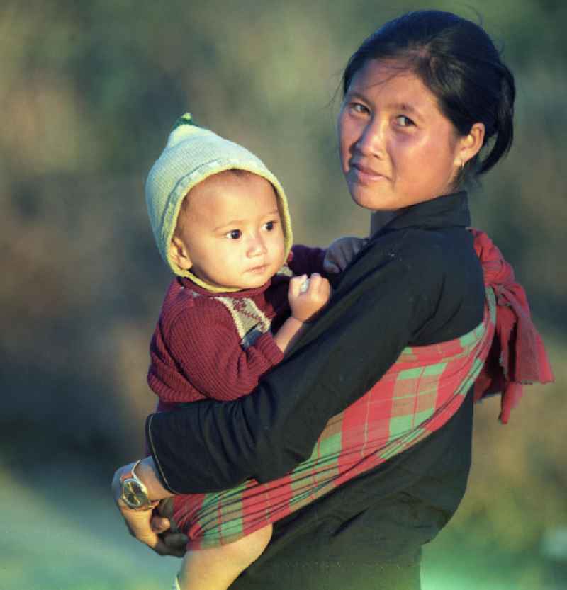Junge Frau mit Baby im Tragetuch aus dem Volksstamm der Meo (auch Hmong) nahe sogenannten 'Ebene der Tonkrüge' in der Provinz Xieng Khouang in der Demokratischen Volksrepublik Laos. Die Hmong waren im Vietnam-Krieg involviert. In dessen Folge gehörten sie zu einer verfolgten und zurückgezogen lebenden Minderheit in Laos.