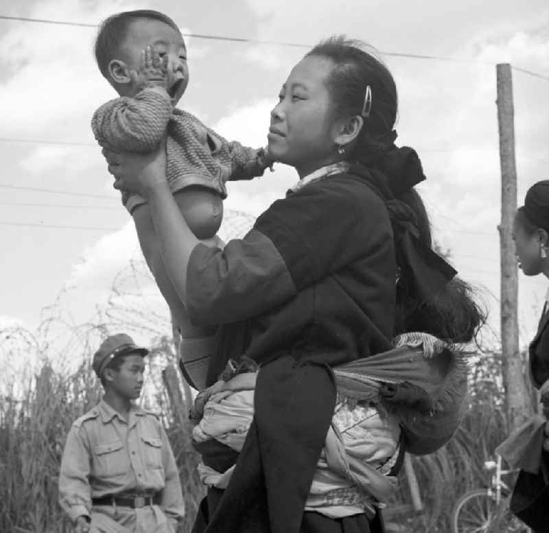 Frau mit Baby aus dem Volksstamm der Meo (auch Hmong) auf einer Straße nahe sogenannten 'Ebene der Tonkrüge' in der Provinz Xieng Khouang in der Demokratischen Volksrepublik Laos. Die Hmong waren im Vietnam-Krieg involviert. In dessen Folge gehörten sie zu einer verfolgten und zurückgezogen lebenden Minderheit in Laos.